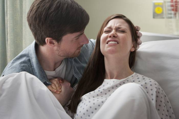 Caucasian man helping girlfriend deliver baby